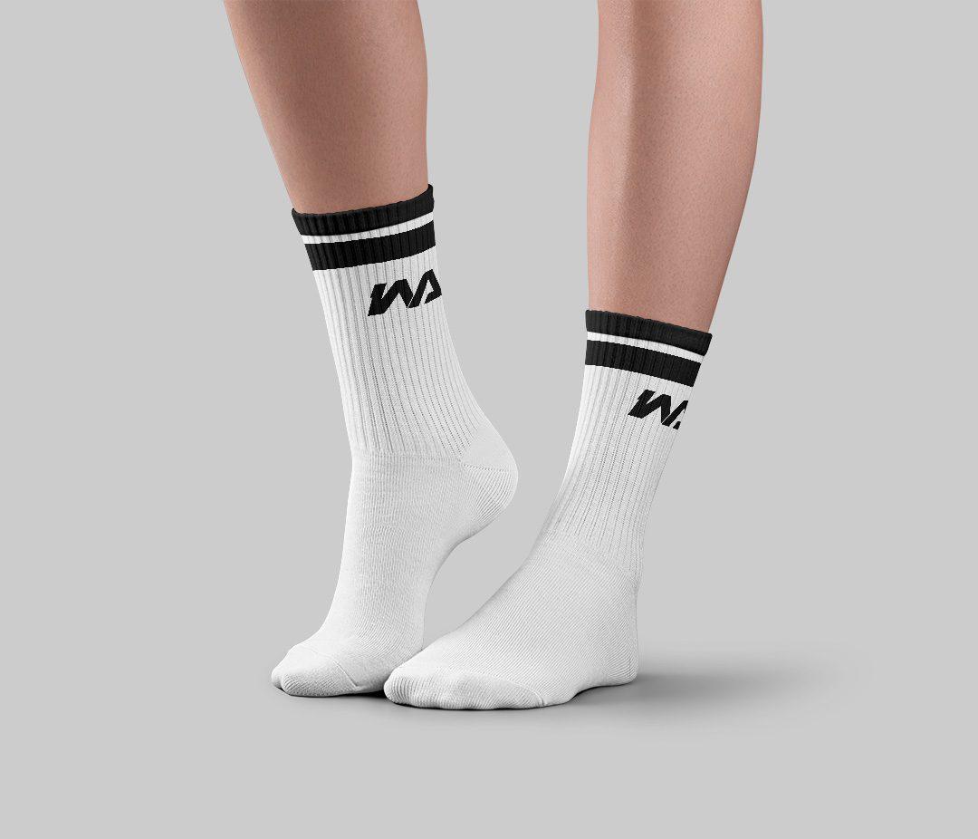 Off-white crew socks with black stripe trim and a black WA logo on the ankle, worn on-foot.